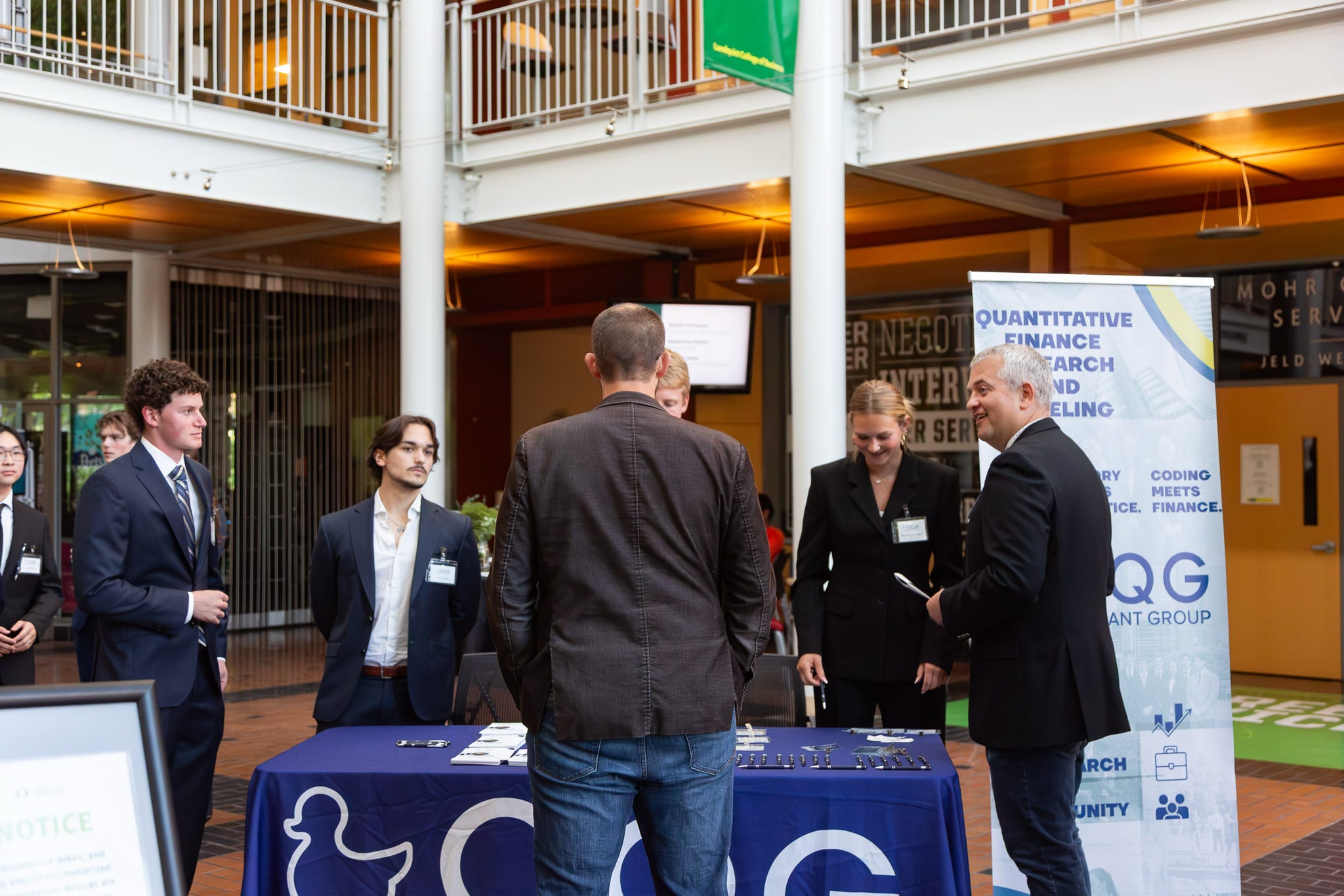 Oregon Quant Group members in suits greeting visitors at the OQG recruitment table