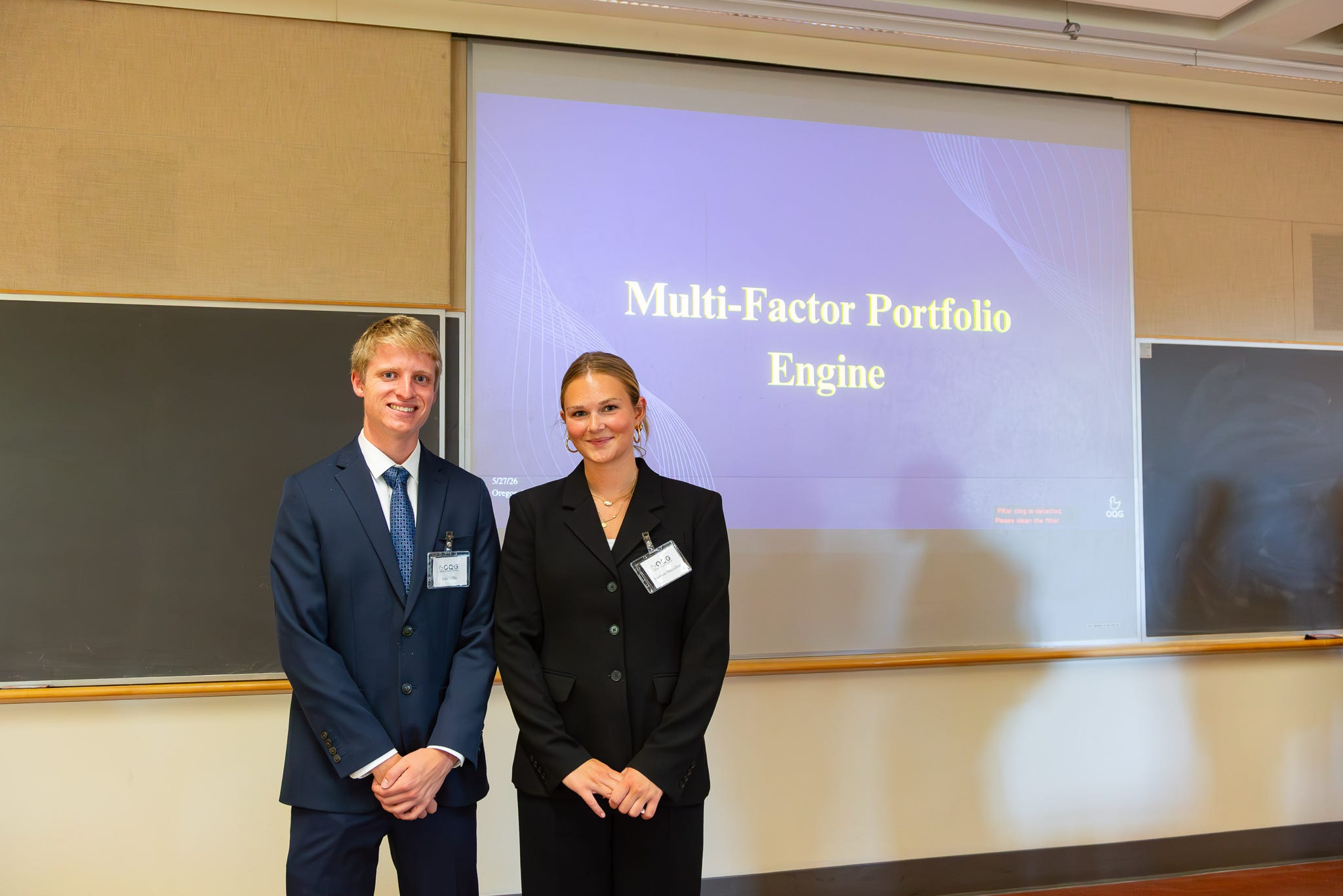 Two members in front of the title slide of their Multi-Factor Portfolio Engine client project