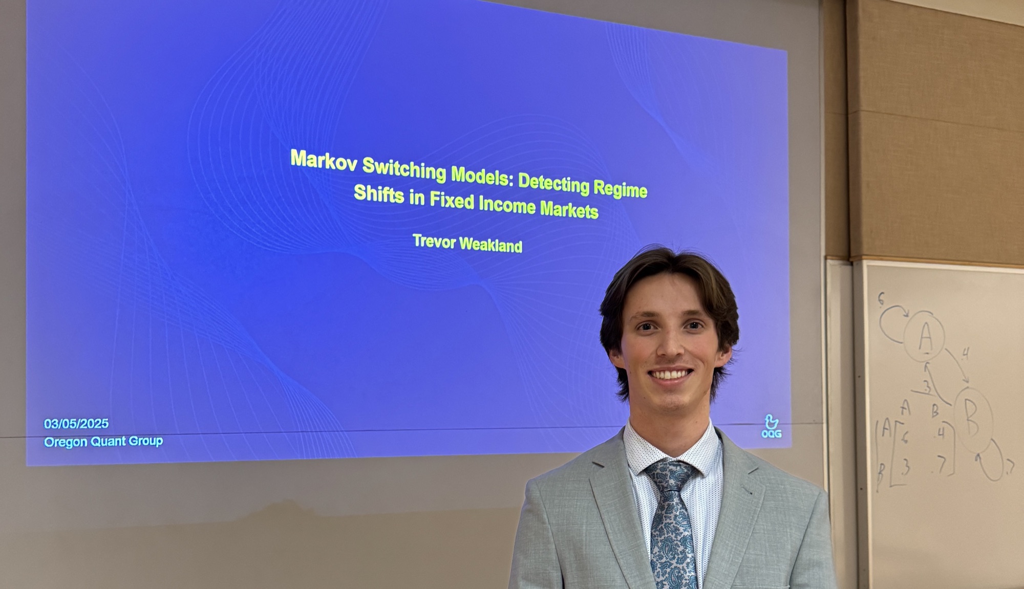 A member presenting Markov switching models, with the derivation on the whiteboard behind him